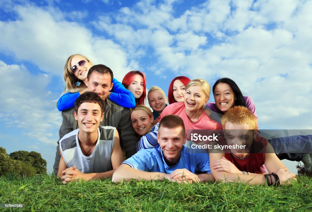 Gran grupo de gente feliz acostado en la hierba. - Foto de stock de Acostado libre de derechos