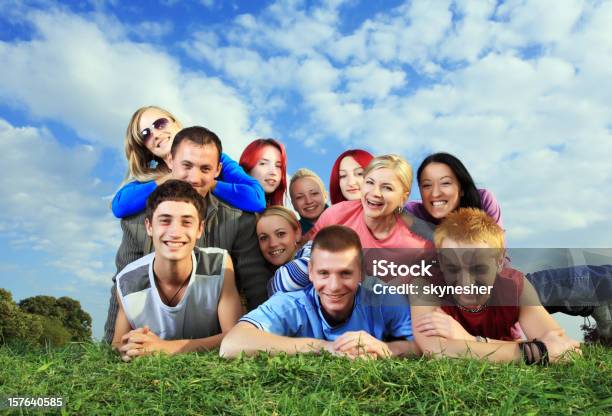 Gran Grupo De Gente Feliz Acostado En La Hierba Foto de stock y más banco de imágenes de Acostado - Acostado, Actividad, Adolescente