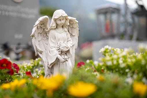 A beautiful statue of a female angel standing in flowers.