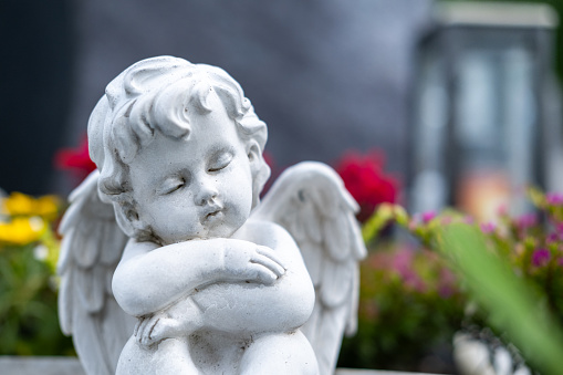 A statue of an angel sleeping in flowers.