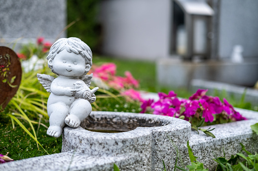 Cute funny angel sitting on a grave.