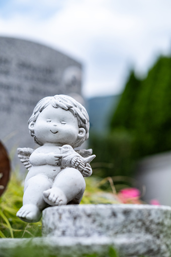 Cute funny angel sitting on a grave.