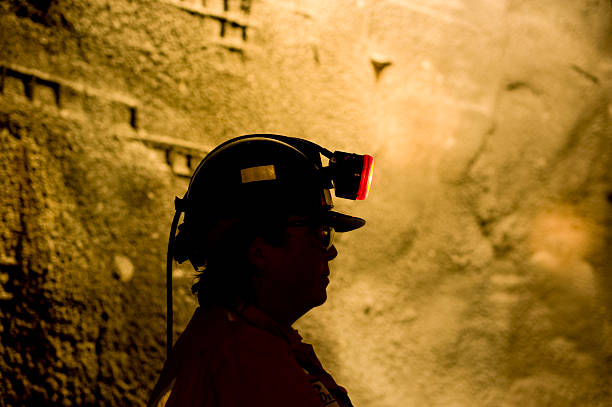 Woman Underground Mine Worker with Lamp On. stock photo