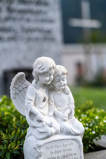 Angel embracing a child, statue.