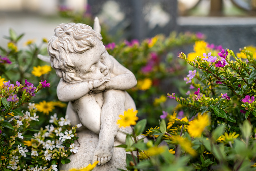 A statue of an angel sitting in flowers.