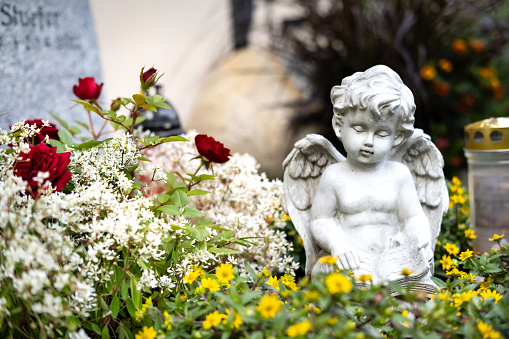 A statue of an angel sitting in flowers.