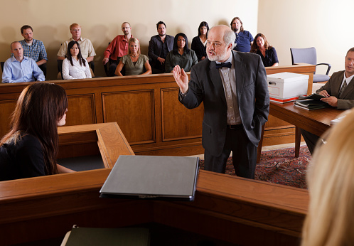 A lawyer questioning a witness in front of the jury in a courtroom.