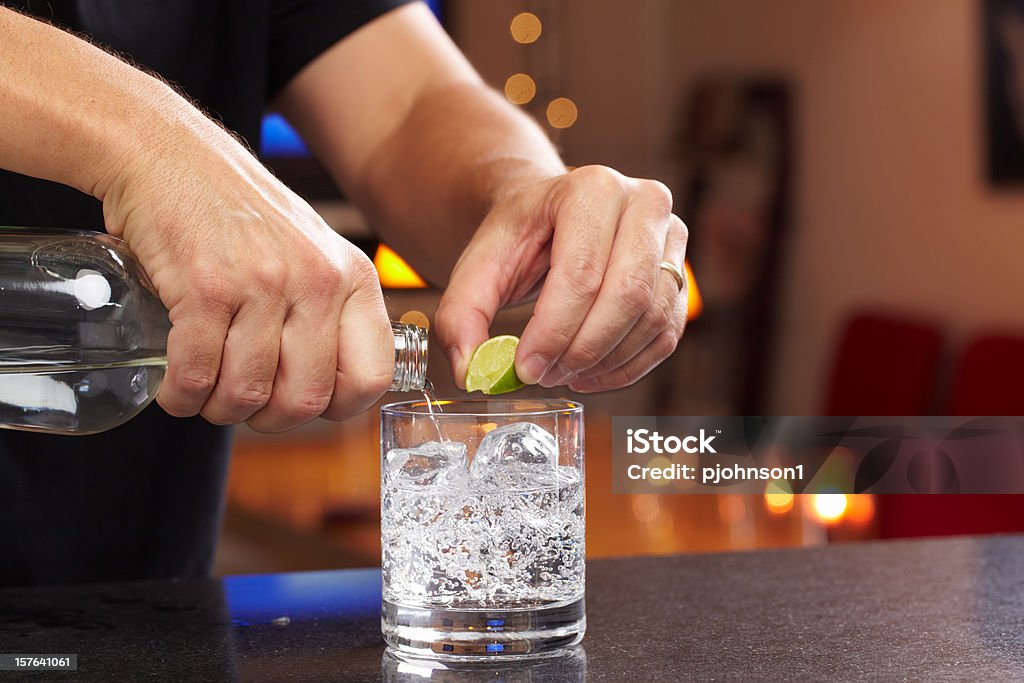 Bartender Hands squeezing lime and pouring gin or vodka into lowball glass with seltzer or tonic.  Professionally shot, color corrected, exported 16 bit depth, retouched and saved for maximum image quality.  Vodka Stock Photo