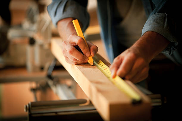 carpenter messen einem holz plank - heimwerken stock-fotos und bilder