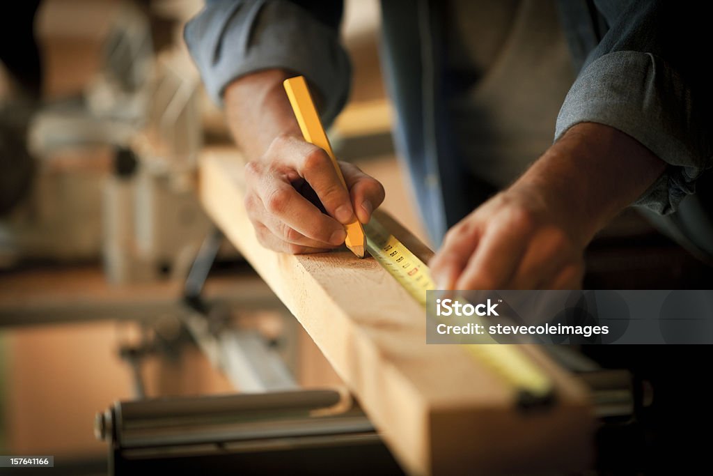 Carpenter Measuring a Wooden Plank Closeup cropped view of a carpenter marking a measurement on a wooden plank. Horizontal shot. Carpenter Stock Photo