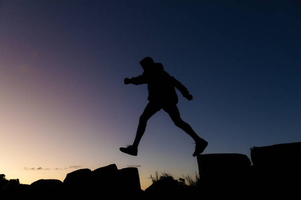 istock Young man on a hike silhouetted against a sunset 1576414642