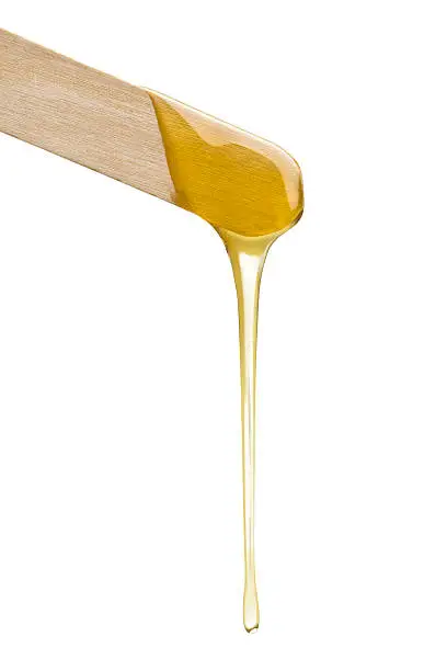 Wax dripping from a spatula isolated on white.