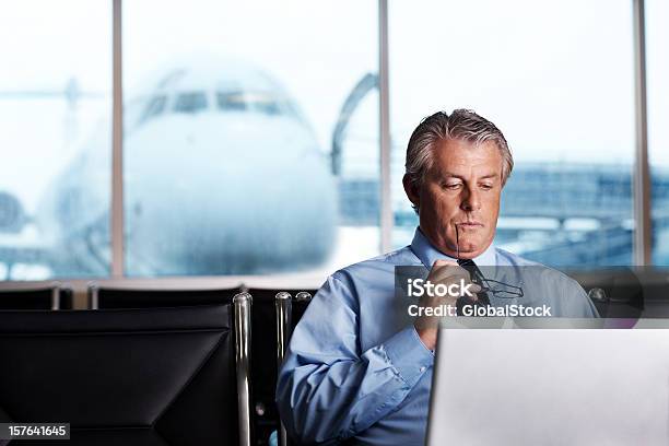 Maturo Uomo Daffari Utilizzando Il Computer Portatile Con Aeroplano In Background - Fotografie stock e altre immagini di Abbigliamento