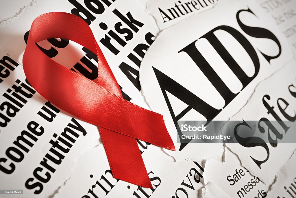 Red AIDS ribbon on headlines about aspects of the disease  AIDS Stock Photo