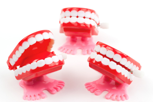 Plastic toy teeth on grey background. Abstract minimal composition. Space for text