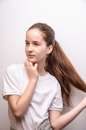 remove birthmarks on surface face, girl touching thick healthy hair, look away, wearing white T-shirt over white paint wall texture