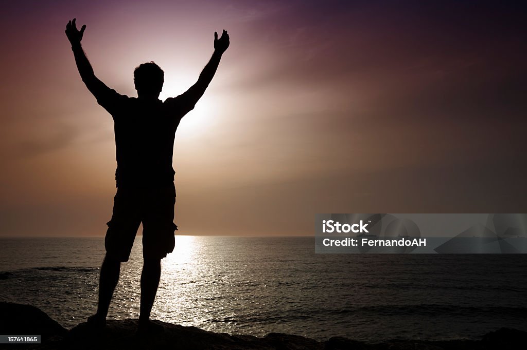 Silhouette of a man at sunset.  Praying Stock Photo