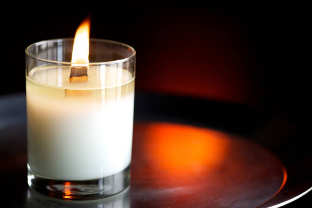 Yellow candle with a white flower against a white background