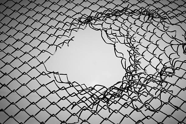 Section of wire mesh with a hole in the middle hole in the wire mesh prison escape stock pictures, royalty-free photos & images