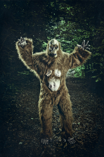 Bigfoot in the middle of a dirty road in north carolina, waving his arms, pretending to be scary.