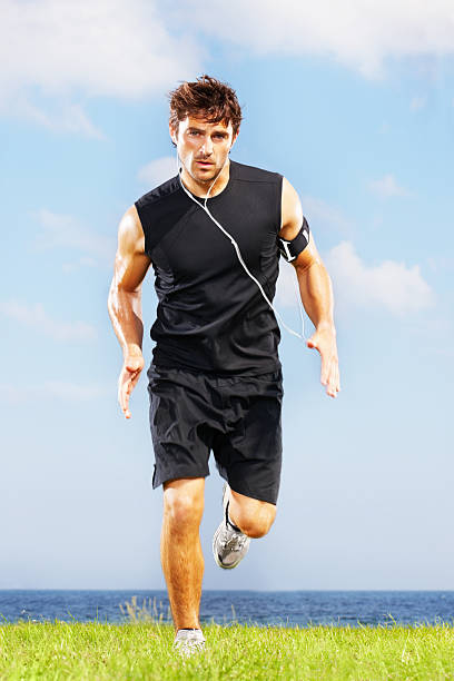 istock Young guy running on grass against calm sea 157643129
