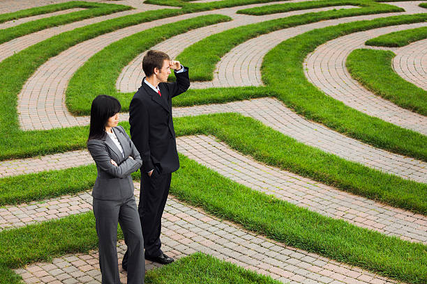 Searching Maze for Career Job, Business Corporate Future, Strategy Solutions A business man and business woman, two people, Caucasian and Asian, wandering in the corporate maze searching for a way to their occupation, job, and career future, or contemplating their company financial future and seeking solutions. Concept of business problem solving and and management strategy. rat race stock pictures, royalty-free photos & images
