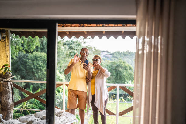 istock Senior couple doing a video call using mobile phone on the balcony at a hotel 1576432353