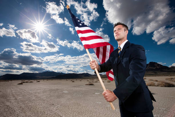 Happy cheerful teenage boy with American flag on blue sky background
