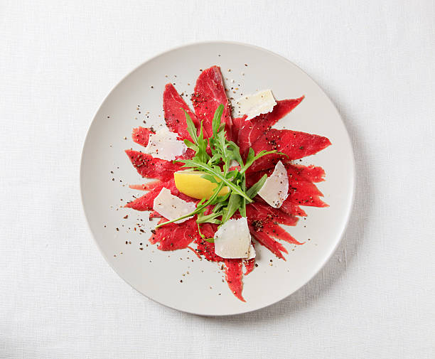 Carpaccio Thin slices of raw beef fillet garnished arugula and Parmesan carpaccio parmesan cheese beef raw stock pictures, royalty-free photos & images