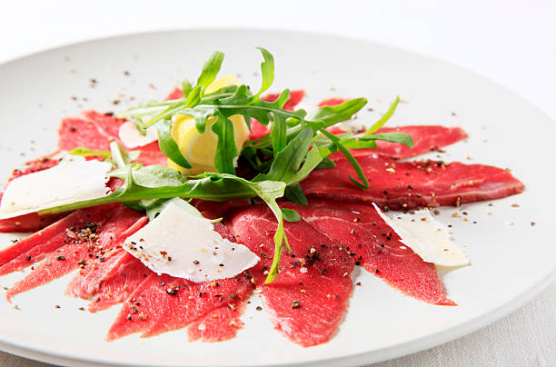 Carpaccio Thin slices of raw beef fillet garnished arugula and Parmesan carpaccio parmesan cheese beef raw stock pictures, royalty-free photos & images