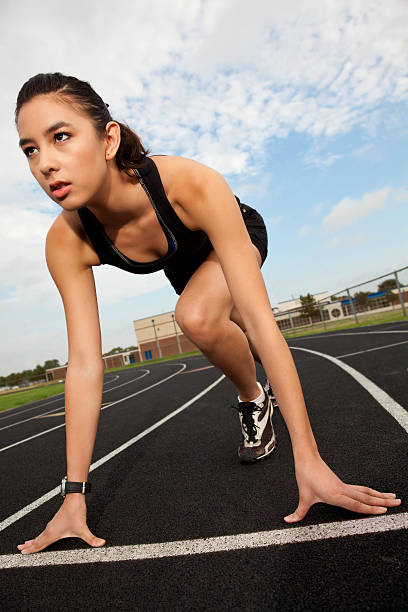 intense corridore di donna sul blocco di partenza per l'atletica - blocco di partenza per latletica foto e immagini stock