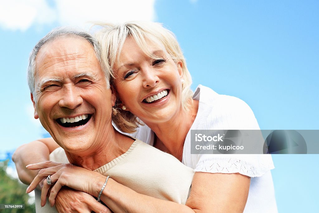 Close-up of a Старший мужчина piggybacking его жена против неба. - Стоковые фото 50-59 лет роялти-фри