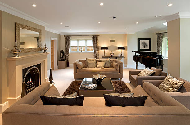 luxury lounge Luxurious living room in an expensive new home that has been decorated and furnished by a leading Interior Designer. The room comprises two large double seat and two single seat settees, a beautiful lit fireplace, a grand piano and lots of elegant silk cushions. expensive grand piano stock pictures, royalty-free photos & images