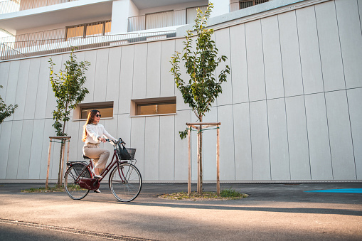 Caucasian businesswoman  riding a bicycle to work. She is wearing smart casual clothing arriving to the office in a business district.