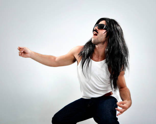 Photo of a young man with long hair playing electric guitar on stage.