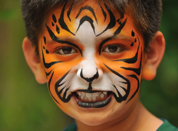 Cute boy with painted face as a lion, having fun, studio shot