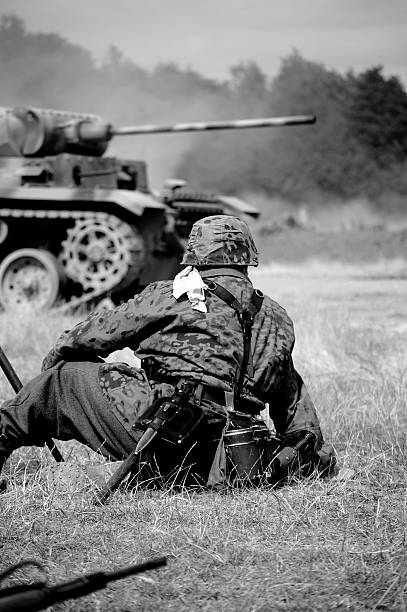 Soldier near Tank. WW2 Era German soldier sits in the foreground with german Panzer Tank in the background.Picture has been aged to give the feel of a period shot. battle photos stock pictures, royalty-free photos & images