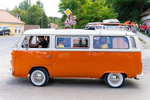 July 27. 2023, orange, old, Volkswagen, minibus, waving, tourists, Valley of Arts Festival, Kapolcs, Hungary.