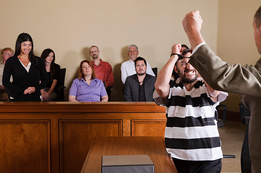 A man in a prison uniform celebrating his acquittal in court.