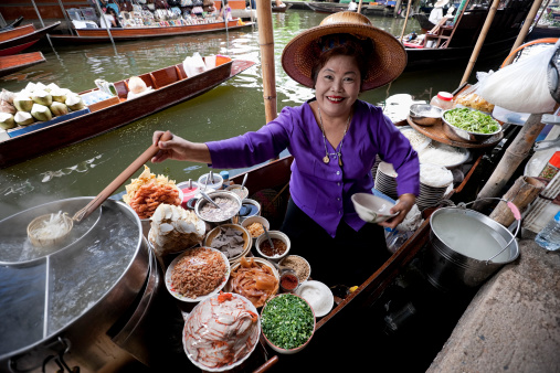 Food vendor at the Damnoen Saduak Floating Market preparing Thai style noodles, Thailand.