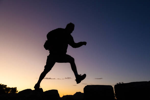 istock Man on a hike silhouetted against a sunset sky 1576457039