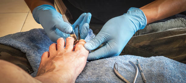 Pedicure - person with blue plastic gloves cuts client's toenails stock photo