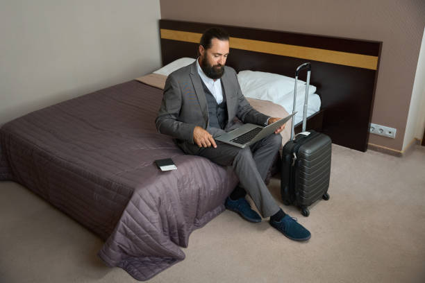 istock Traveling businessman sat down with a laptop on the bed 1576460285