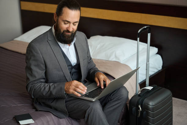 istock Traveling man sat down with a laptop on the bed 1576460794