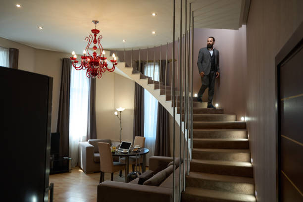 mann mittleren alters geht die treppe hinunter ins wohnzimmer - vehicle interior staircase residential structure indoors stock-fotos und bilder