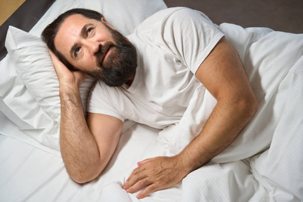 istock Bearded male is resting in a big bed 1576460922
