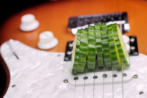 An electric guitar used as a cucumber-slicer. Focus on the slices. AdobeRGB