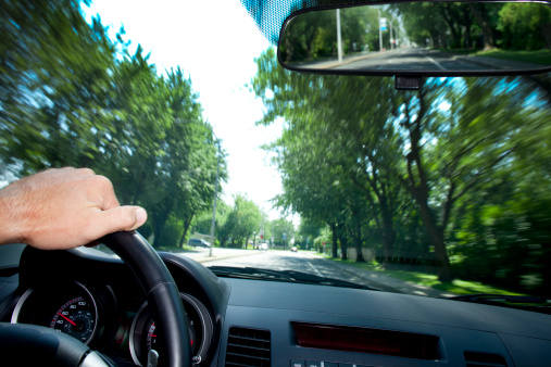View through windshield of moving car. Showing speed blur. Horizontal. With detail in rear view mirror. 