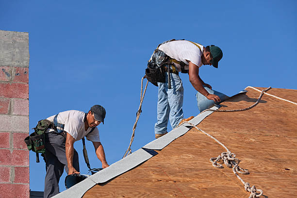 Dangerous Jobs Roofers on an 8-12 pitch roof laying under-layment before installing roof tile.  safety harness photos stock pictures, royalty-free photos & images