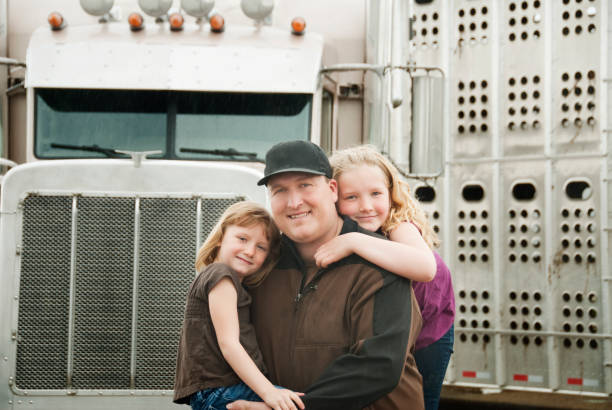 Father and two daughters on the front of a truck, smiling stock photo